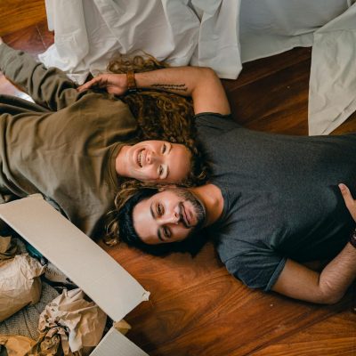 Photo by Ketut Subiyanto From above of young smiling diverse couple in casual clothing relaxing on floor near carton boxes while unpacking belongings in new contemporary apartment