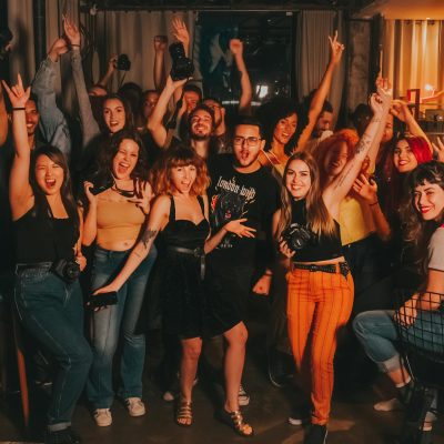 High angle of excited young diverse friends in casual outfits with arms raised yelling happily while celebrating project success in modern workspace