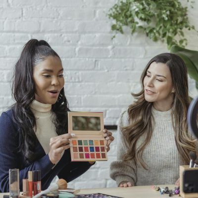 Photo by George Milton Young diverse ladies recording vlog about makeup products on smartphone